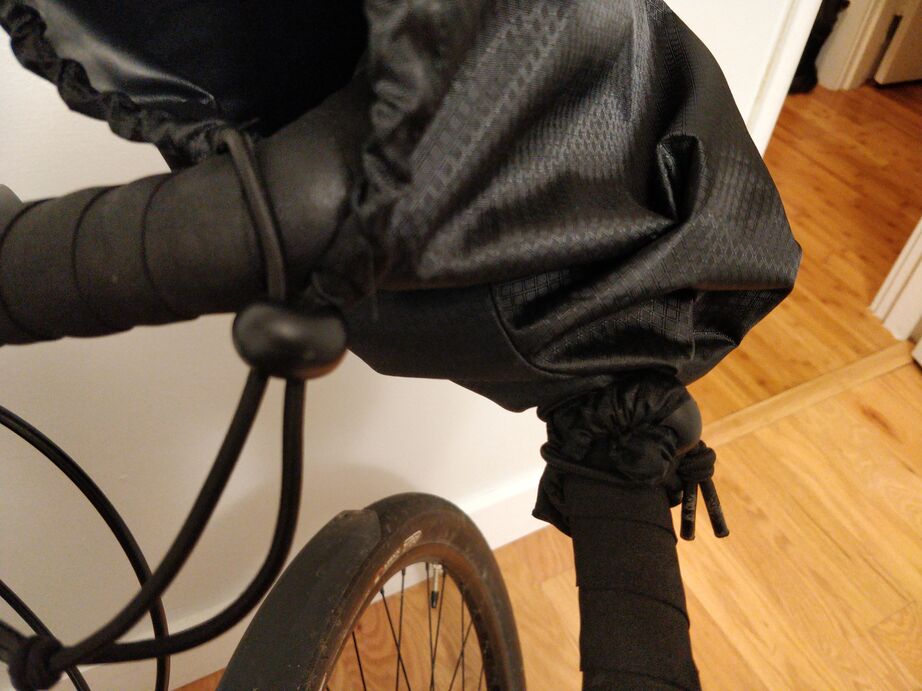 Photo of a pogie installed on drop handlebars, zoomed in on how the cords are attached to the bars